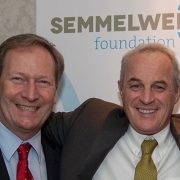 Picture of Bernhard Küenburg and Didier Pittet smiling in front of a poster with the Semmelweis Foundation logo on it