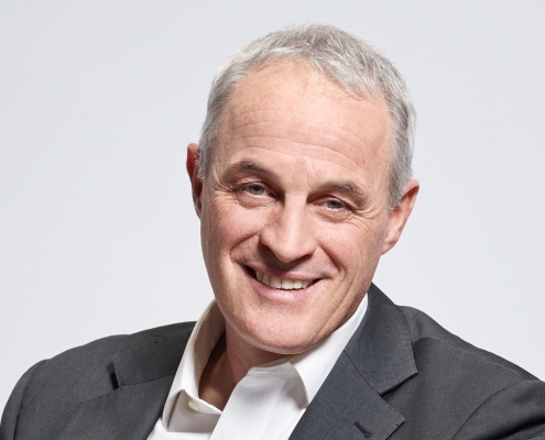 Portrait of Didier Pittet smiling in a grey jacket