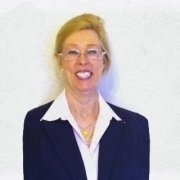 Portrait of Dr. Sharon L. Kurtz in a white shirt and dark blue jacket in front of a white wall