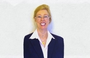 Portrait of Dr. Sharon L. Kurtz in a white shirt and dark blue jacket in front of a white wall